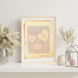 Handmade typewriter art on handmade, recycled, deckled-edged cotton paper. The repeated word “plants” is hand typed in black on a typewriter. The use of black and red letters, along with negative space, forms a visual of a houseplant in the center of the page. The piece rests in a neutral frame on a white shelf styled with dried pampas grass, a glass terrarium, and pink textured vases to the sides. At the bottom of the art, the website “www.PlantsAreMyType.com” appears in red.