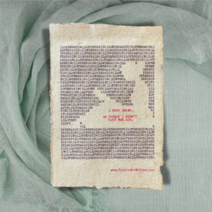 The words, "I Love Reading" are typed repeatedly on handmade, recycled cotton paper to form an image of a person seated, reading a book, using black ink and negative space. The words, “I read books. Of course I didn't vote for him.” are typed in red inside of the outline. The website www.plantsaremytype.com is typed at the bottom right corner of the page. The art sits atop a green linen background.