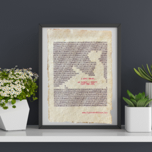 The words, "I Love Reading" are typed repeatedly on handmade, recycled cotton paper to form an image of a person seated, reading a book, using black ink and negative space. The words, “I read books. Of course I didn't vote for him.” are typed in red inside of the outline. The website www.plantsaremytype.com is typed at the bottom right corner of the page. The art is shown in a black frame on a ledge with plants on both sides of the framed art.