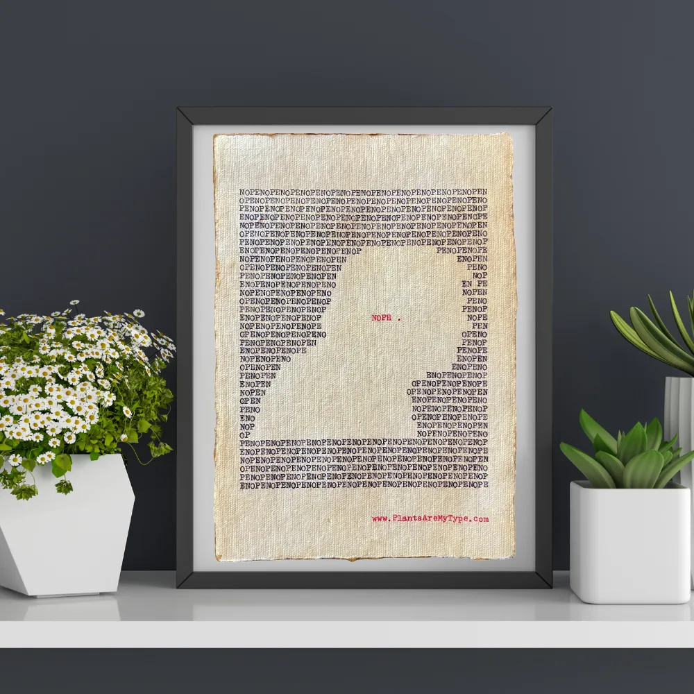 The word, "nope" is typed repeatedly on handmade, recycled cotton paper to form an outline of a man’s right-side portrait using black ink and negative space. The word, “nope.” is typed in red inside of the outline. The website www.plantsaremytype.com is typed at the bottom right corner of the page. The art is shown in a black frame on a ledge with plants on both sides of the framed art.