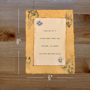 Typewriter art on a wooden background. There are guides showing the paper size, 6"x8". The page is stamped with real flowers and displays a poem about love.