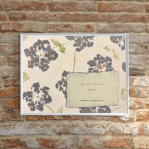 Artwork inside a white frame displayed on a brick wall. Art made using pigment from real plants as a backdrop. Atop, on handmade cotton paper, are the hand-typed plant common name and botanical name as well as the area the plants were collected.